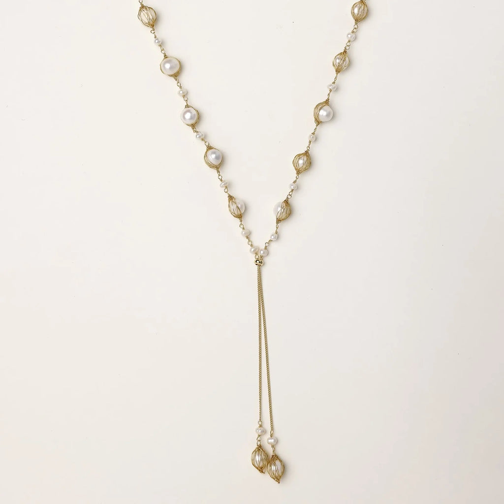 Adjustable gold lariat necklace with freshwater pearls nested in delicate cage settings and Y-shaped tassel drop