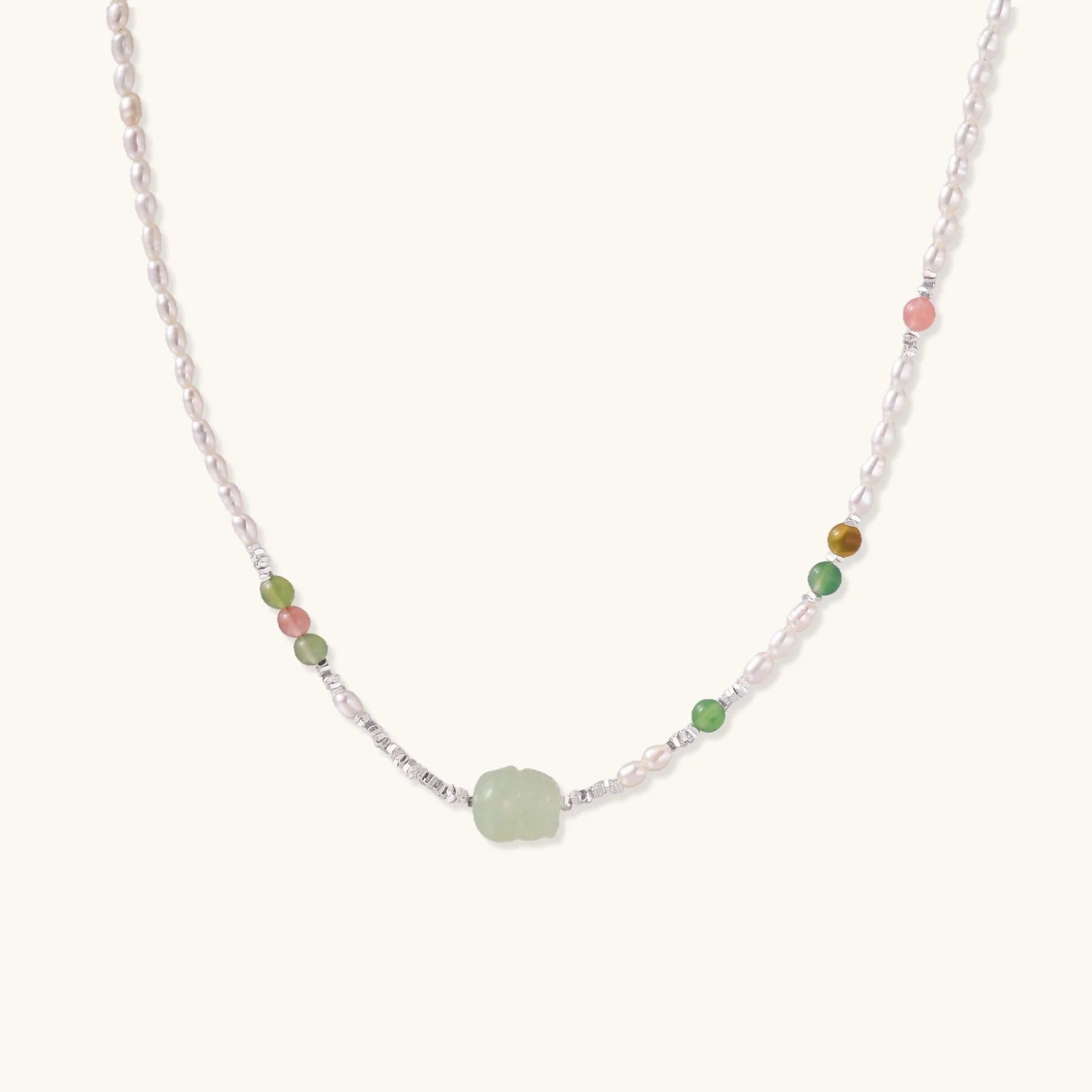 Delicate pearl necklace with pale green serpentine jade centerpiece and colorful agate beads on cream background