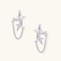 Silver star studs with crescent moon cutouts and zirconia stones connected by delicate chains on white background