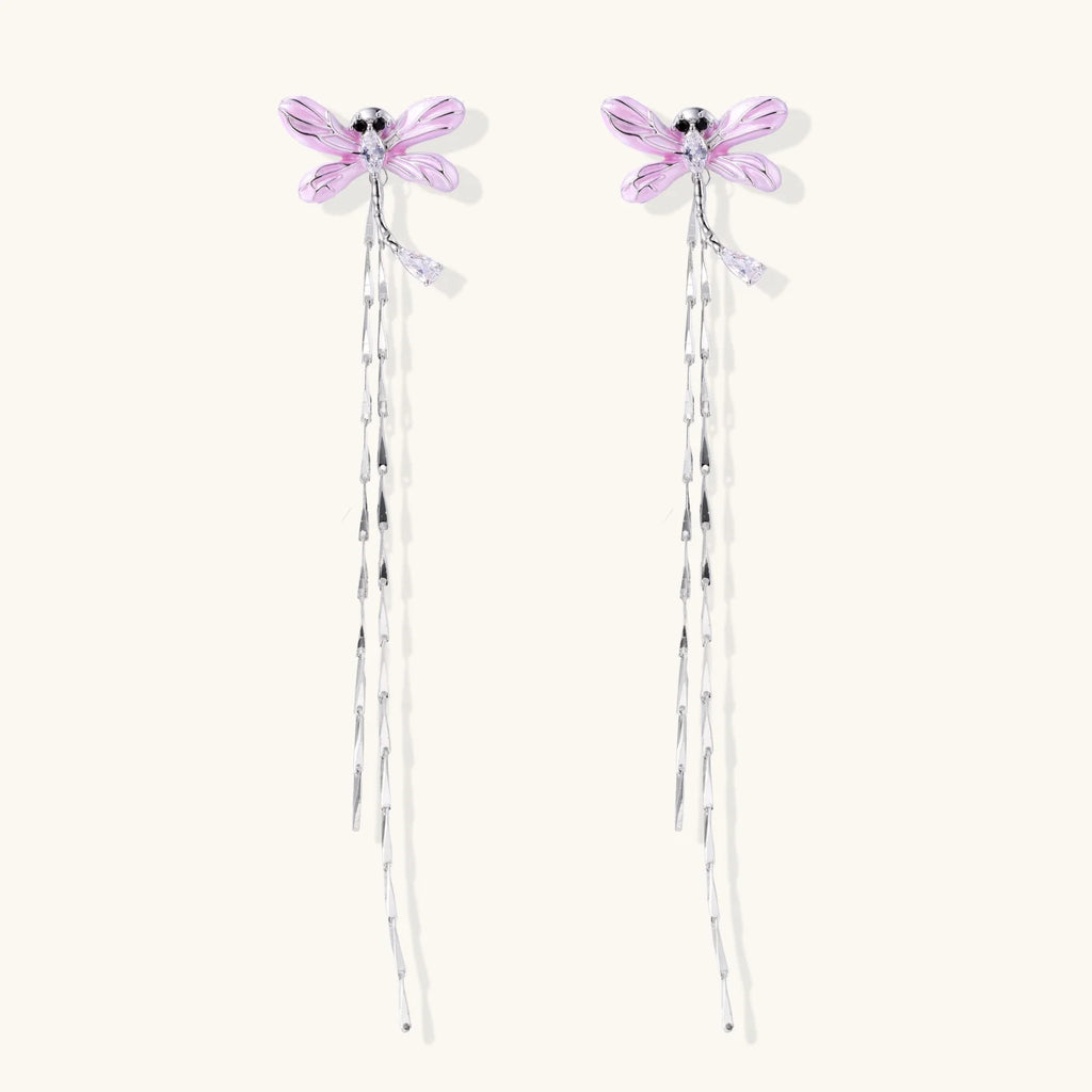 Long drop earrings with translucent lavender enamel dragonfly wings and white gold plated segmented bodies on white background