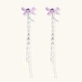 Long drop earrings with translucent lavender enamel dragonfly wings and white gold plated segmented bodies on white background