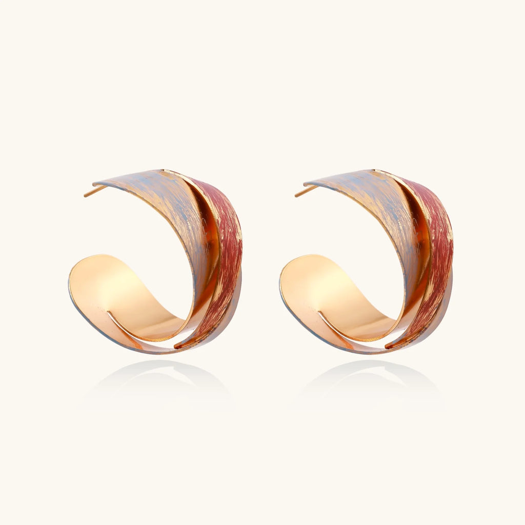 Sculptural gold-plated hoop earrings with diagonal purple and coral enamel stripes in twisted ribbon design