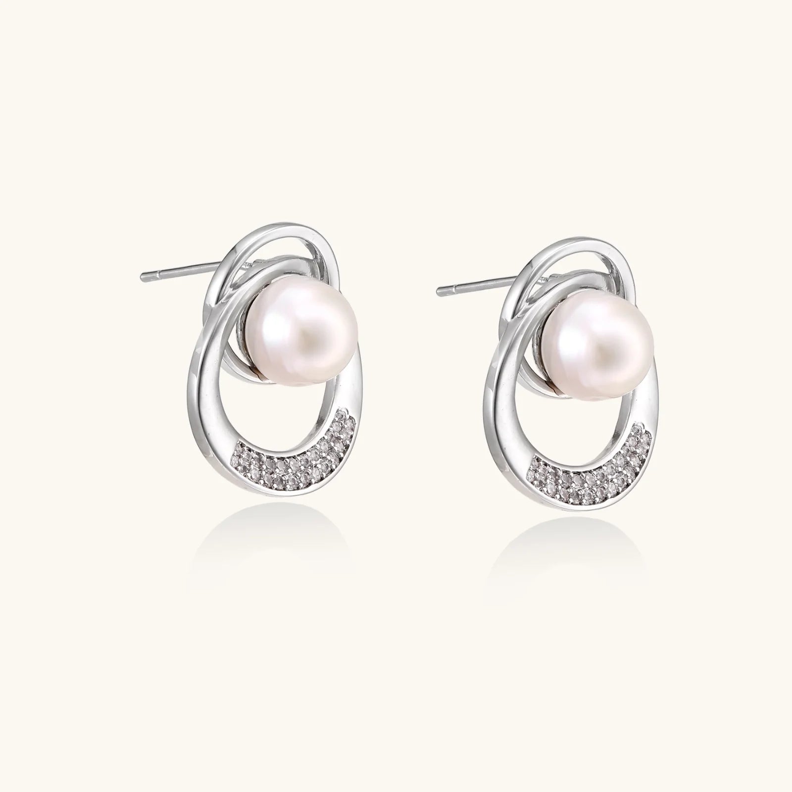 White gold-plated brass earrings with circular design, freshwater pearl center, and diamond accents
