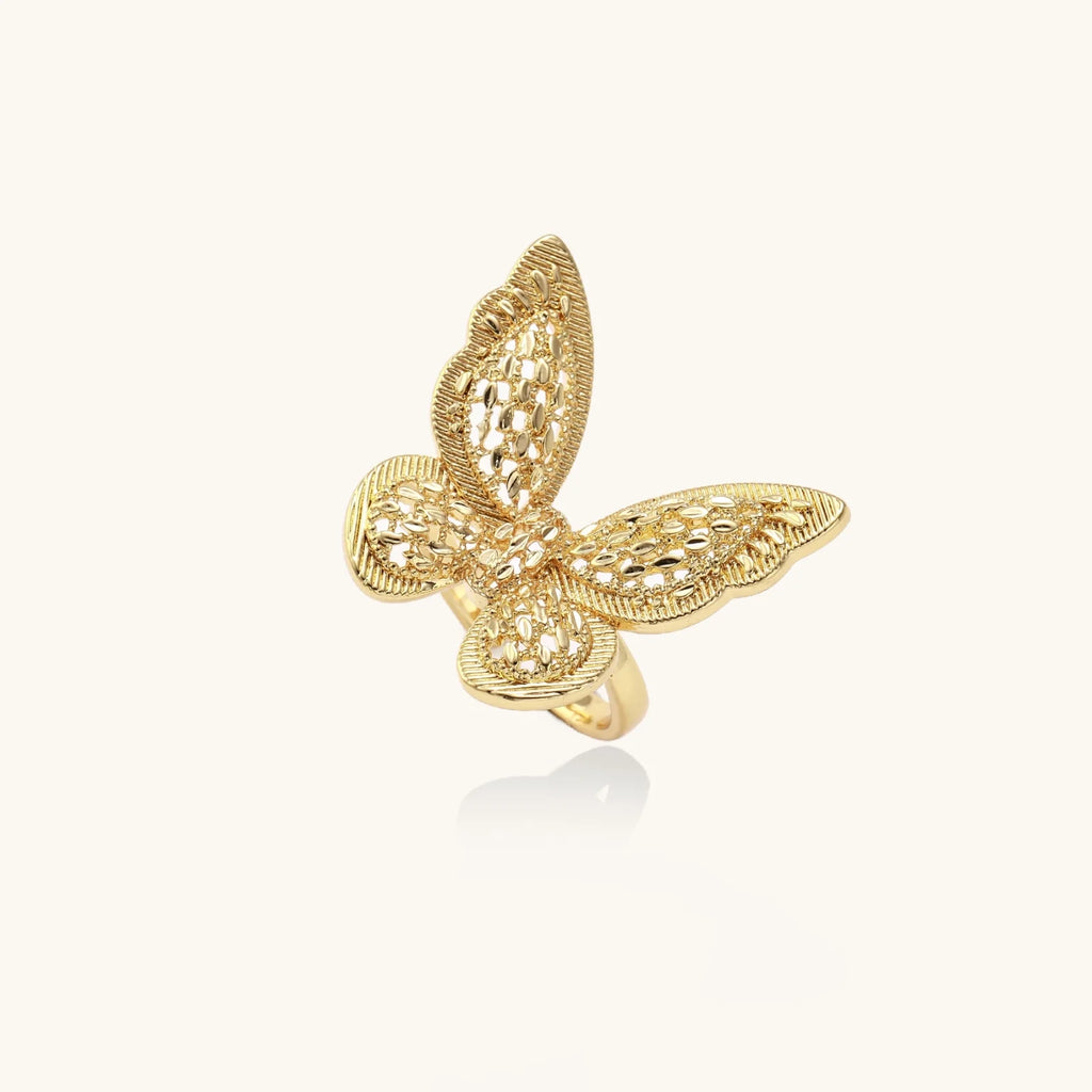 Intricate gold-plated butterfly ring with filigree cutout wings and adjustable band on white background.